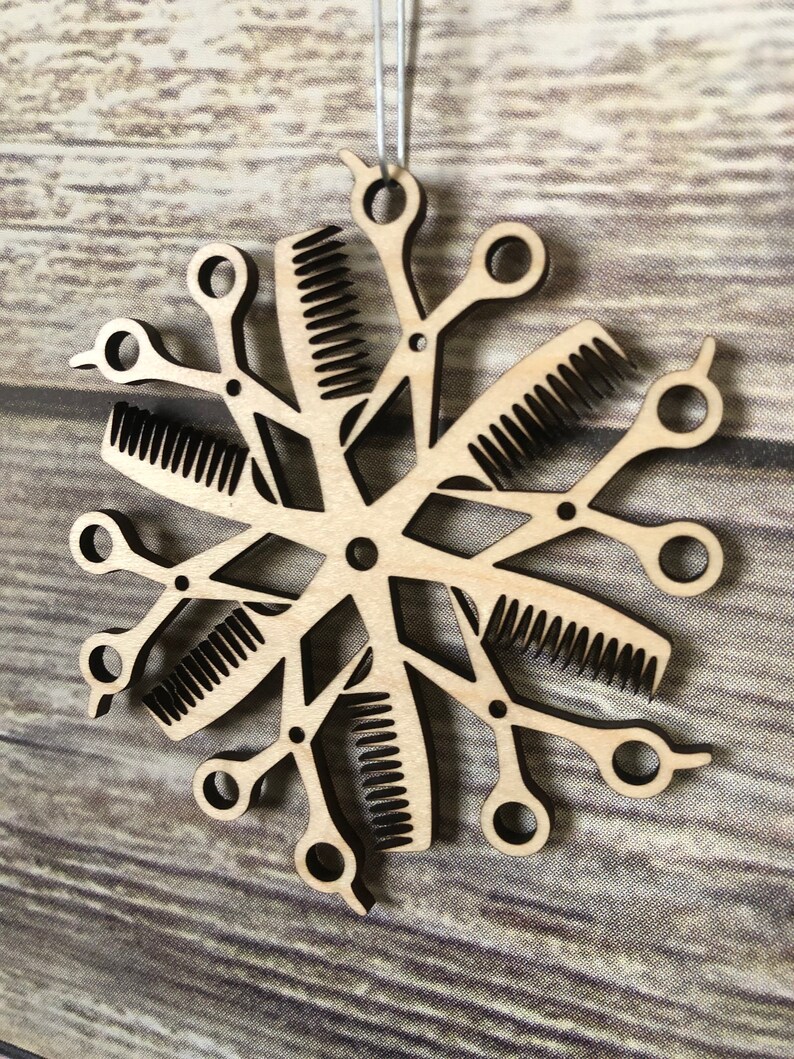 May include: A wooden Christmas ornament shaped like a snowflake, made from multiple pairs of scissors and combs.
