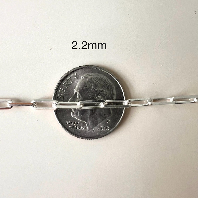 May include: A silver chain link necklace with a 2.2mm width, shown next to a US dime for scale.