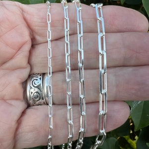 May include: Four silver chains of different widths, all with a rectangular link design. The chains are laid out in a row, with the widest chain at the bottom and the narrowest chain at the top.