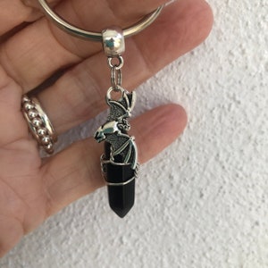 May include: A black crystal point with a silver bat charm attached to a silver key ring.