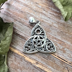 May include: Silver pendant featuring a triple moon and sun symbol with a pentagram in the center. The pendant is in the shape of a triquetra, a Celtic knot.