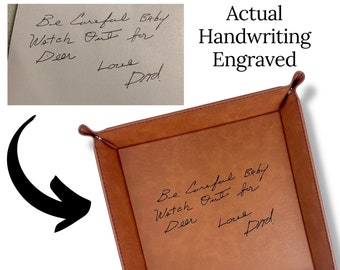 May include: A brown leather tray with a handwritten message engraved on the inside. The message reads "Be Careful Baby Watch Out for Deer Love Dad".