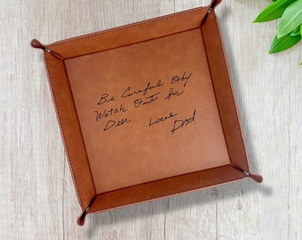 May include: A square brown valet tray with raised corners secured by metal fasteners. The center features black engraved cursive text that reads: Be Careful Baby Watch Out for Deer Love Dad. The tray has a smooth, matte finish and flat base.