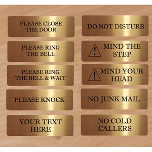 May include: Eight gold-colored metal signs with black text. The signs have various messages, including "Please Close the Door", "Do Not Disturb", "Please Ring the Bell", "Mind the Step", "Please Ring the Bell & Wait", "Mind Your Head", "Please Knock", "No Junk Mail", "Your Text Here", and "No Cold Callers".