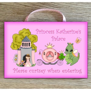May include: Pink wooden sign with a princess theme. It says "Princess Katherine's Palace" and "Please curtsy when entering". There is a cartoon image of a princess, a carriage, a dragon, and a frog.