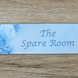 May include: A light blue door sign with a floral design and the text "The Spare Room".