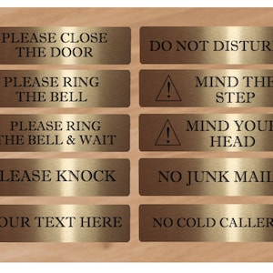 May include: Eight gold-colored metal signs with black text. The signs read: "Please Close The Door", "Do Not Disturb", "Please Ring The Bell", "Mind The Step", "Please Ring The Bell & Wait", "Mind Your Head", "Please Knock", "No Junk Mail", "Your Text Here", and "No Cold Callers".