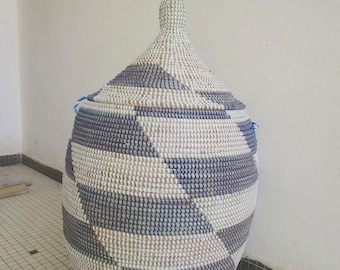 May include: A large, woven storage basket with a lid. The basket is made of natural materials and has a geometric pattern in shades of white, blue, and purple.