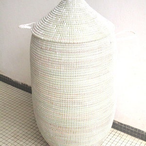 May include: White woven storage basket with a lid. The basket is tall and cylindrical with a pointed top. The basket is made of natural materials and has a subtle pattern.