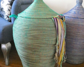 May include: Two large woven storage baskets with lids. The basket on the left is teal green and the basket on the right is light blue. Both baskets have a woven pattern and are made of natural materials.