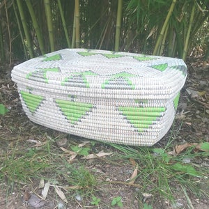 Puede incluir: Una cesta de almacenamiento rectangular tejida en blanco y verde. La cesta está hecha de materiales naturales y tiene un patrón único.