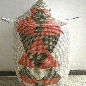 May include: A white woven storage basket with a lid, featuring a geometric pattern of black and orange triangles.