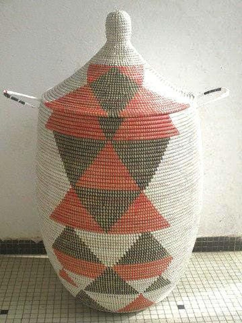 May include: A white woven storage basket with a lid, featuring a geometric pattern of black and orange triangles.