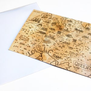 May include: A vintage-style map of Queens, New York, with a brown background and black ink markings. The map shows various neighborhoods and landmarks, including Jamaica, Forest Hills, and Long Island City. The word "QUEENS" is written in a banner at the bottom right corner.