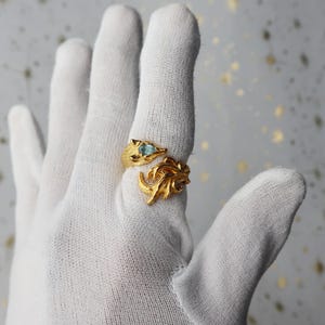 May include: A gold ring with a blue gemstone and a leaf design.