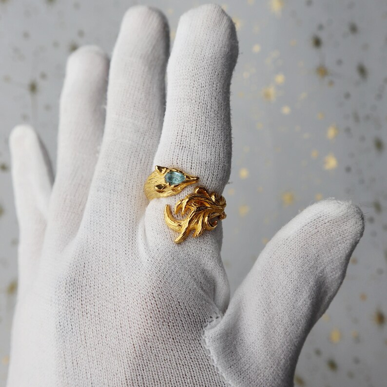 May include: A gold ring with a blue gemstone and a leaf design.