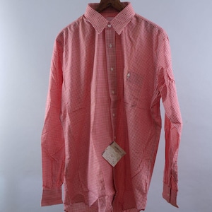 May include: A long-sleeved button-down shirt featuring a red and white gingham check pattern. The shirt has a pointed collar, a front button placket, and a single chest pocket on the left side. A small rectangular paper tag is attached to the front.