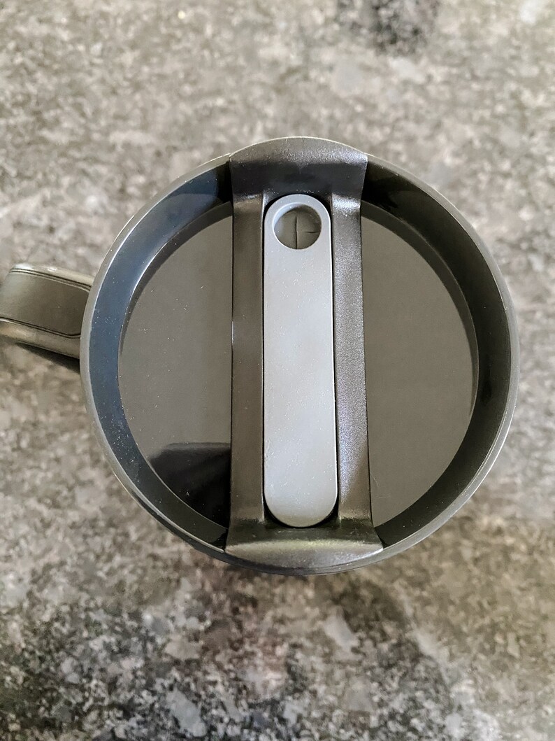 Puede incluir: Taza de viaje negra con tapa deslizante gris. La tapa tiene un peque&ntilde;o agujero para sorber.
