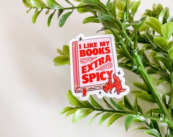 May include: A white sticker with a red book illustration and the text "I like my books extra spicy" with a red flame illustration.