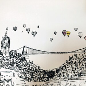 May include: A black and white ink drawing of a suspension bridge with a tower in the foreground. There are multiple hot air balloons in the sky, some with colorful stripes. One balloon has the word "Bristol" written on it.