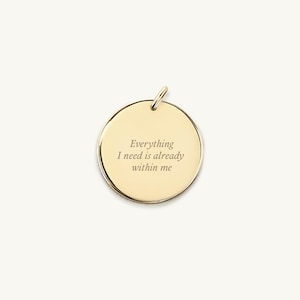 May include: A gold-colored pendant with a circular design. The pendant has a small loop at the top for a chain. The engraved text reads: "Everything I need is already within me."