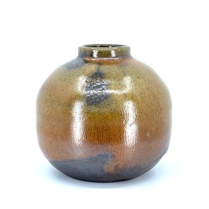 May include: A round, brown ceramic vase with a glossy finish. The vase has a mottled brown and green glaze with a darker brown base.