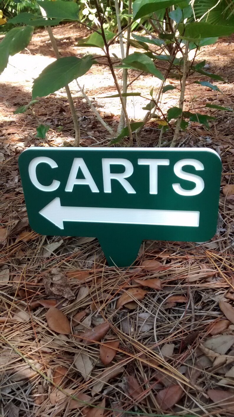 Puede incluir: Un letrero verde con letras blancas y una flecha blanca que apunta hacia la izquierda. El letrero dice "CARTS".
