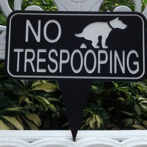 Op de afbeelding: Een zwart-wit bord met de tekst "NO TRESPOOPING" en een silhouet van een hond die poept.