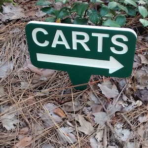 Puede incluir: Un letrero verde con letras blancas y una flecha que apunta hacia la derecha. El letrero dice "CARTS".