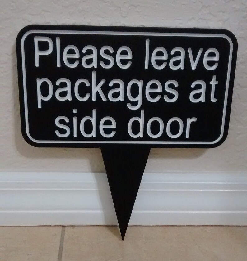 May include: Black sign with white lettering that reads "Please leave packages at side door".
