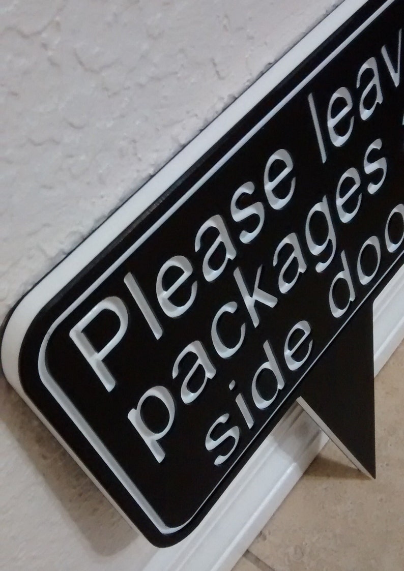 May include: Black and white sign with a speech bubble shape that says "Please leave packages side door".