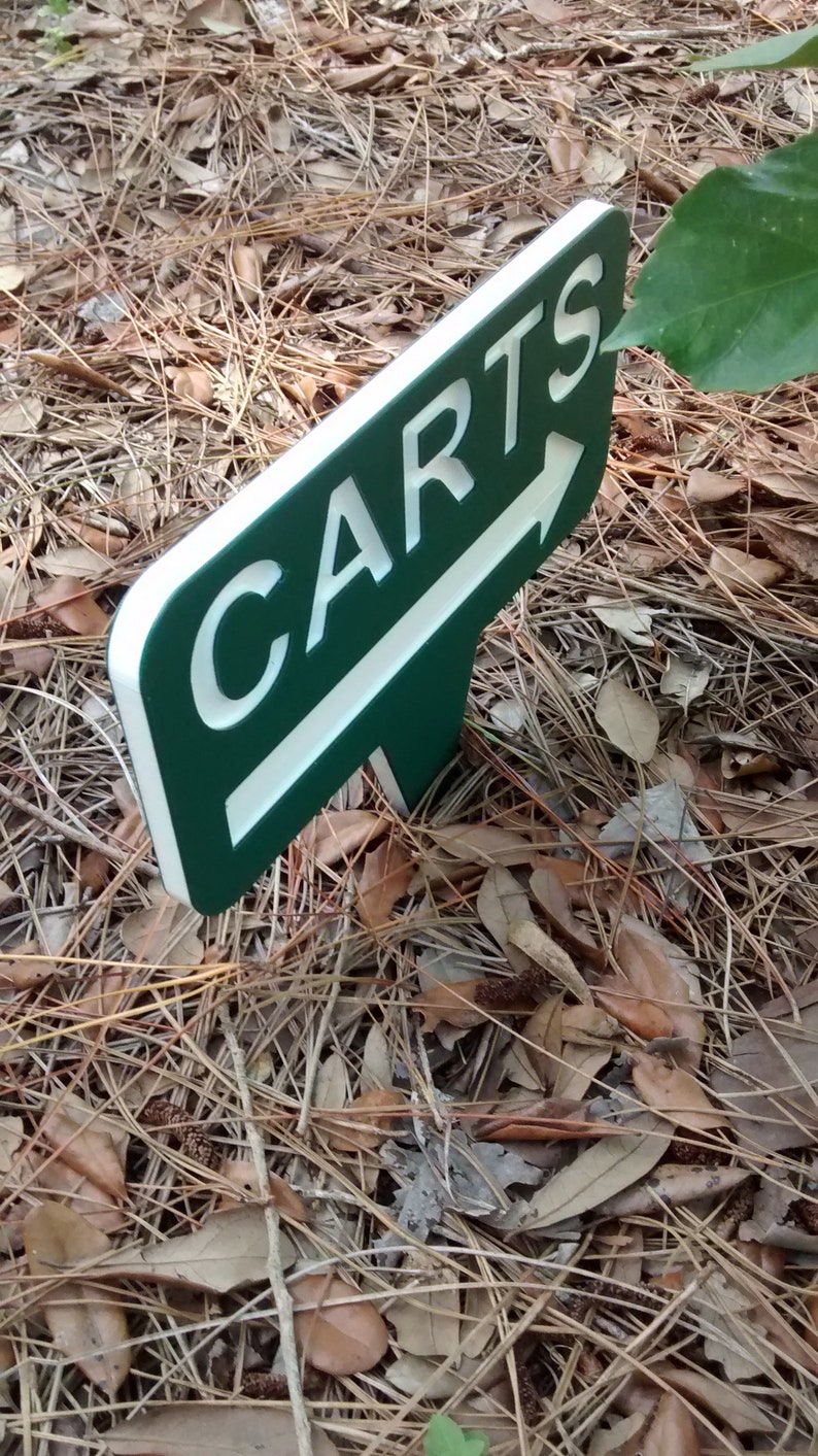 Puede incluir: Un letrero verde y blanco con una flecha que apunta hacia la derecha. El letrero dice "CARTS" en letras blancas.