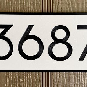 Pode incluir: Placa de n&uacute;mero de casa preta com fundo branco e o n&uacute;mero 3687 em preto.