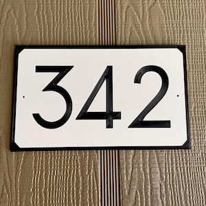 Pode incluir: Placa de n&uacute;mero de casa preto e branco com o n&uacute;mero 342 em um fundo branco.
