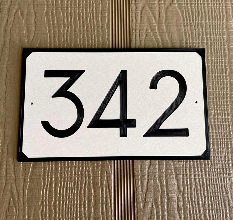 Pode incluir: Placa de n&uacute;mero de casa preto e branco com o n&uacute;mero 342 em um fundo branco.