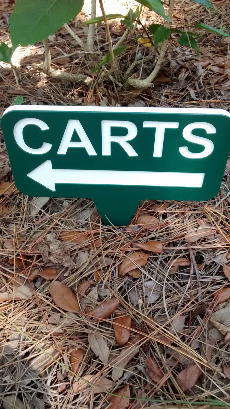 Puede incluir: Un letrero verde y blanco con una flecha blanca apuntando hacia la izquierda y la palabra "CARTS" en letras blancas.