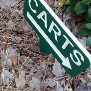 Puede incluir: Un letrero verde y blanco con una flecha que apunta hacia la izquierda. El letrero dice "CARTS".