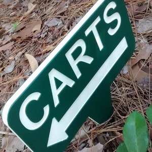 Puede incluir: Un letrero verde y blanco con una flecha apuntando hacia la izquierda y la palabra "CARTS" en letras blancas.