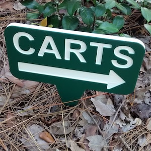 Puede incluir: Un letrero verde y blanco con una flecha que apunta hacia la derecha. El letrero dice "CARTS" en letras blancas.