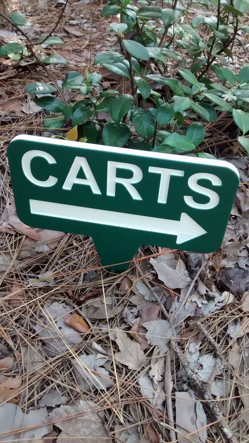 Puede incluir: Un letrero verde y blanco con una flecha que apunta hacia la derecha. El letrero dice "CARTS" en letras blancas.