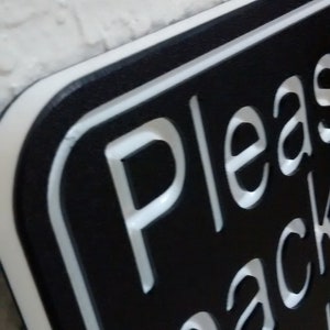 May include: Black sign with white lettering that reads "Please pack side".