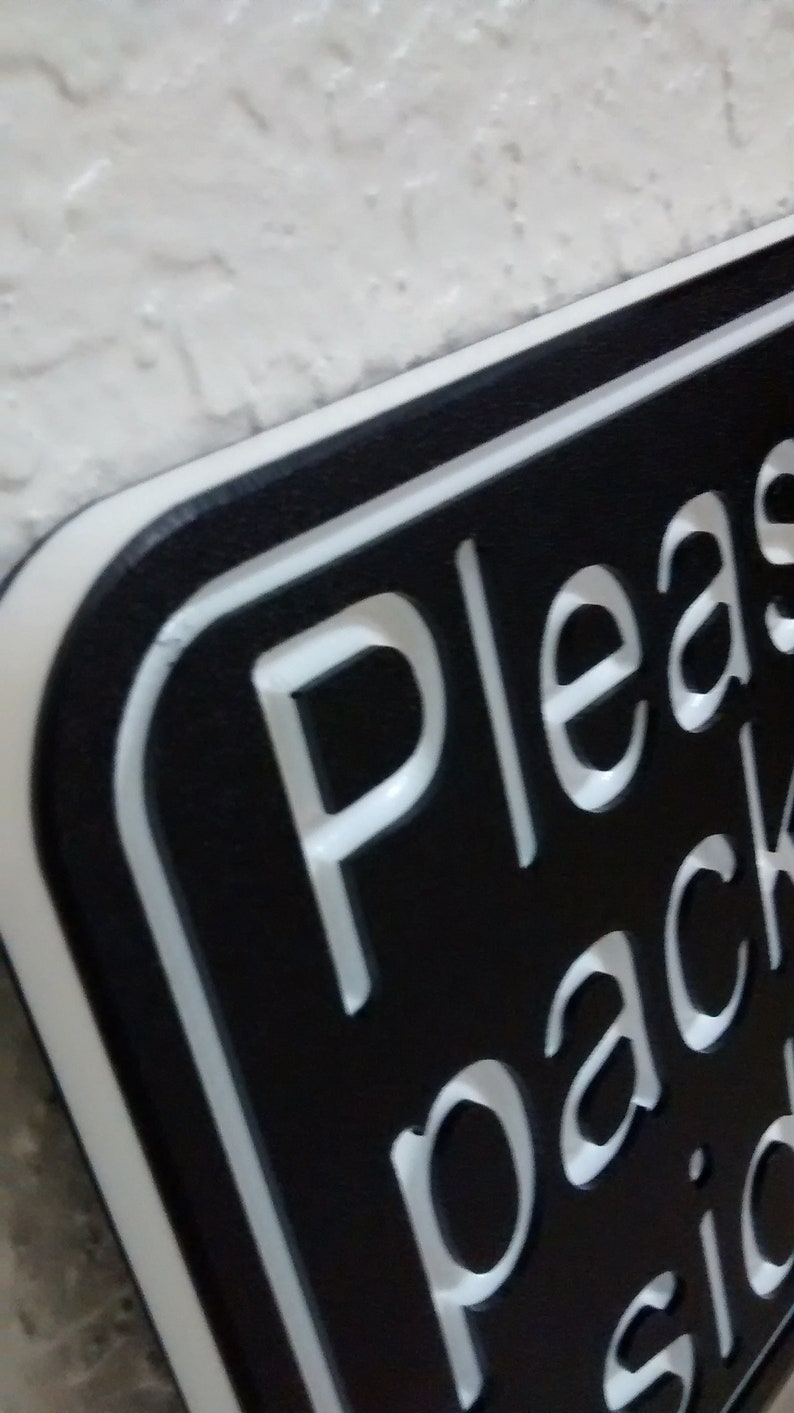 May include: Black sign with white lettering that reads "Please pack side".