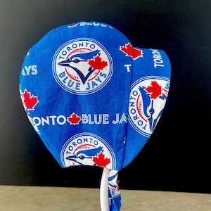 Puede incluir: Sombrero de tela azul y blanco con el logotipo de los Toronto Blue Jays. El sombrero tiene una corbata en la parte posterior.