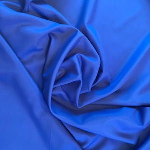 May include: A close-up of a smooth, royal blue fabric with soft folds and wrinkles.