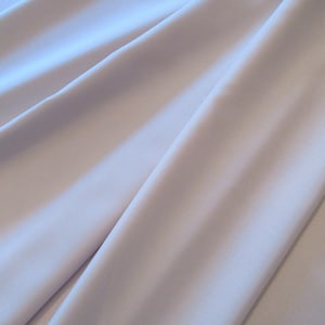 May include: A smooth, light purple fabric with a soft, silky texture. The fabric is folded in a way that shows its drape and flow.