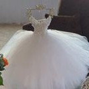 Puede incluir: Un vestido de bola de tul blanco con un corpi&ntilde;o de cuentas y una corona en la parte superior.