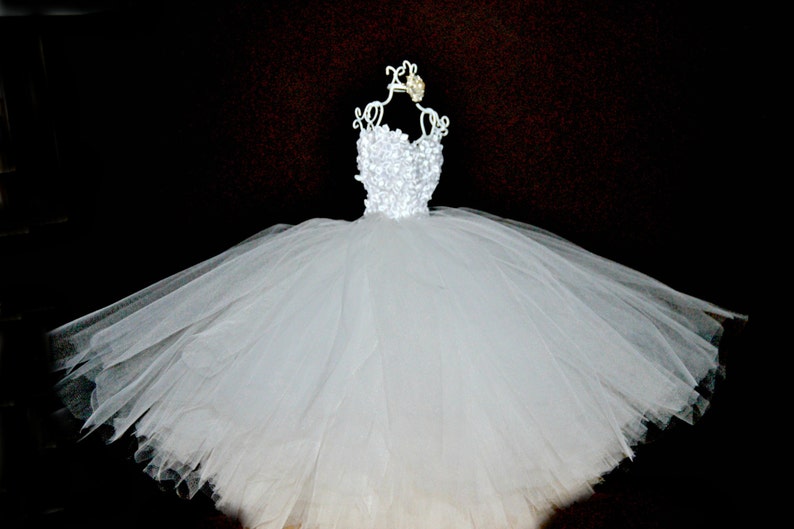 Puede incluir: Un vestido de tul blanco con un corpi&ntilde;o de encaje blanco en un maniqu&iacute; blanco.