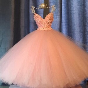 Puede incluir: Un vestido de bola de tul rosa con un escote de coraz&oacute;n y un corpi&ntilde;o adornado con flores 3D.
