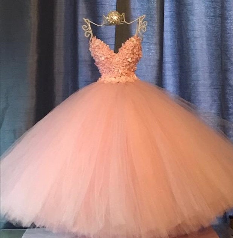 Puede incluir: Un vestido de bola de tul rosa con un escote de coraz&oacute;n y un corpi&ntilde;o adornado con flores 3D.
