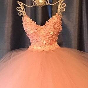 Puede incluir: Un vestido de bola de tul rosa claro con un escote de coraz&oacute;n y un corpi&ntilde;o cubierto de aplicaciones florales rosas.